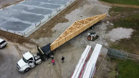 Roof truss getting delivered by semi on the job site.