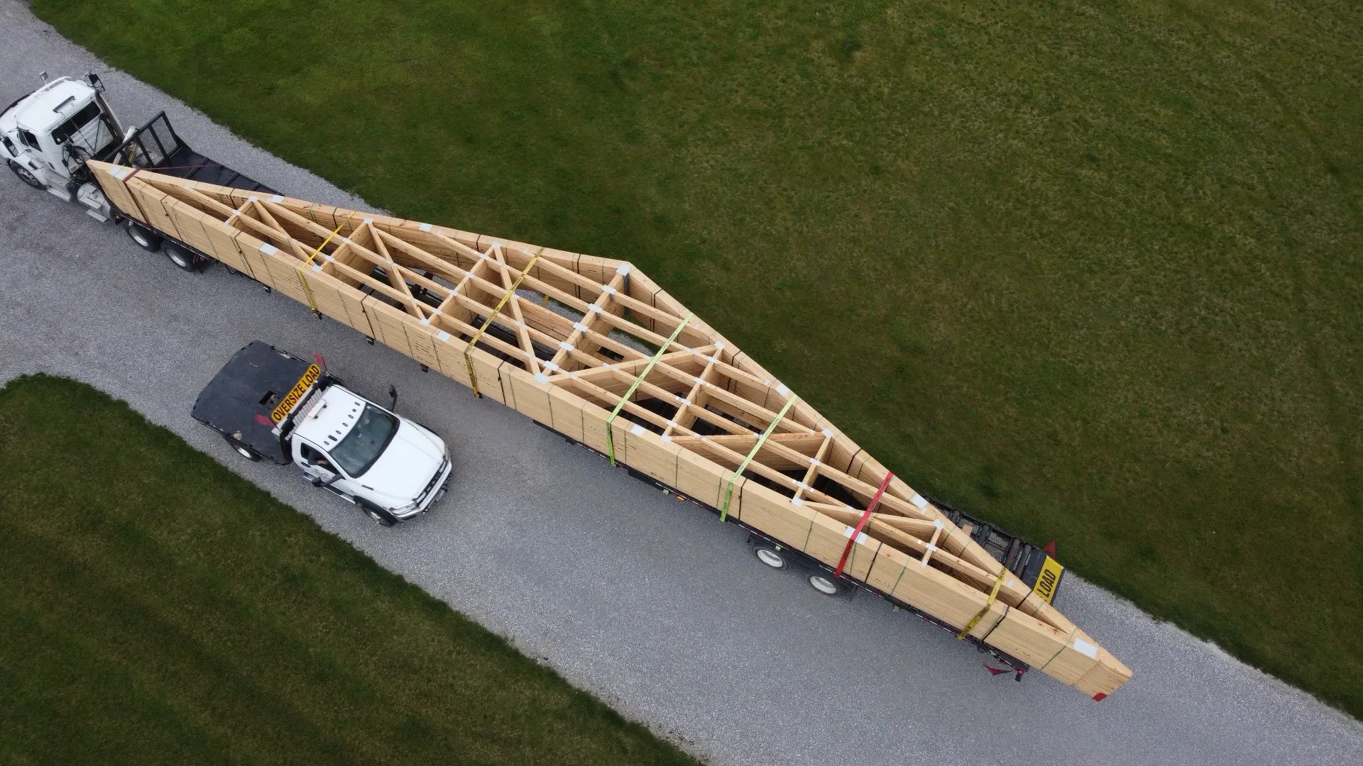 Roof truss getting delivered on a semi with an escort truck beside him.